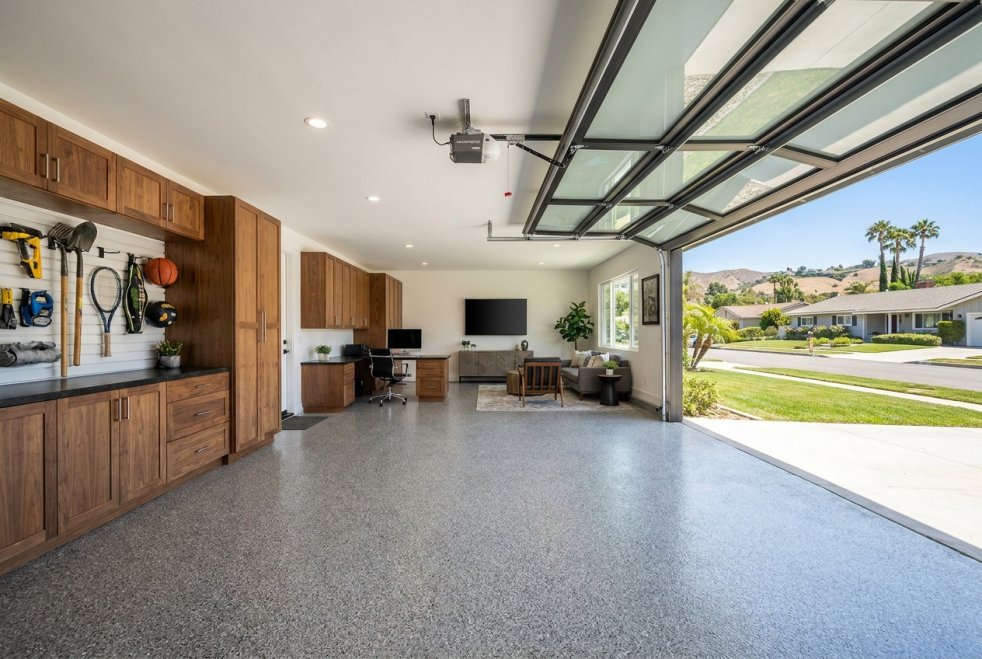 Renovated garage with custom storage cabinets, workbench, office space, and open garage door in a Woodland Hills home
